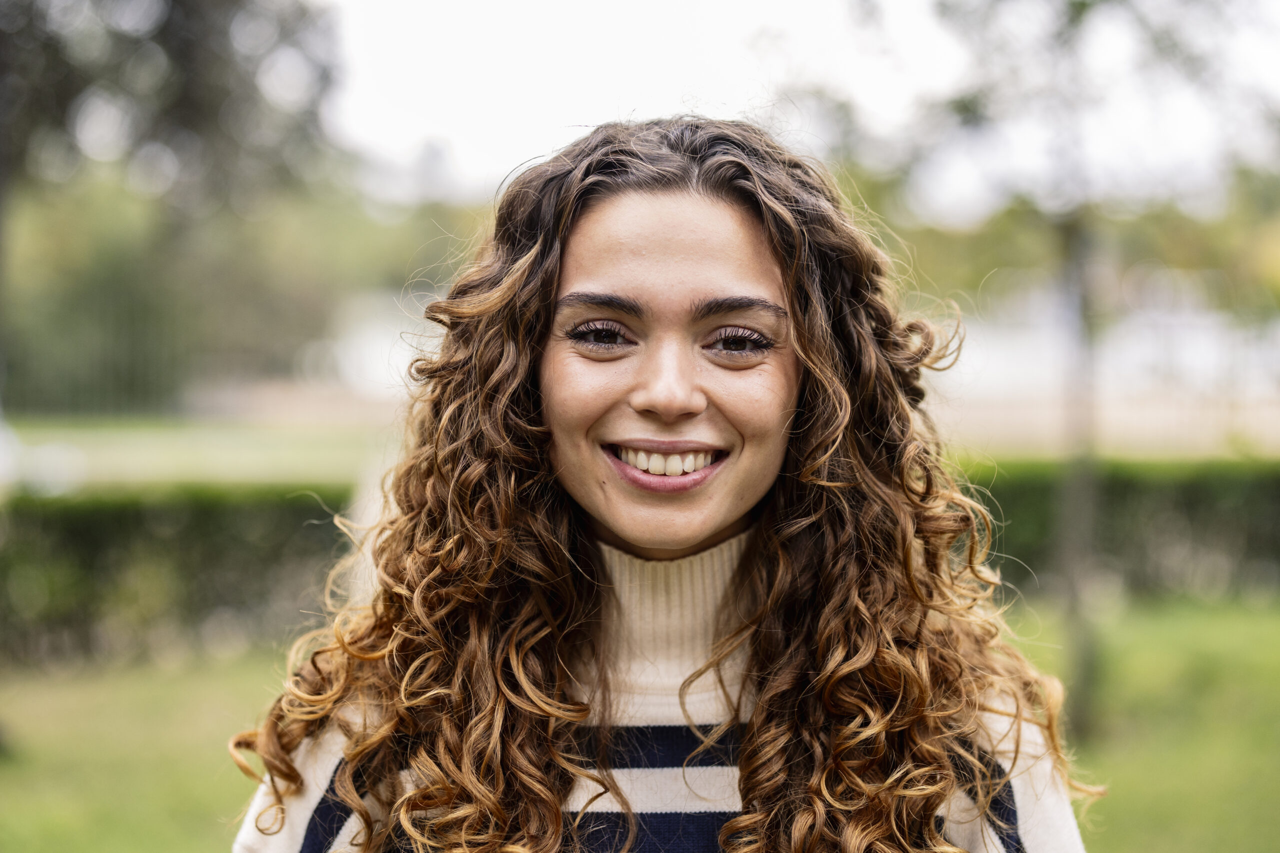 portrait of young caucasian woman with blonde curly hair smiling and looking at camera